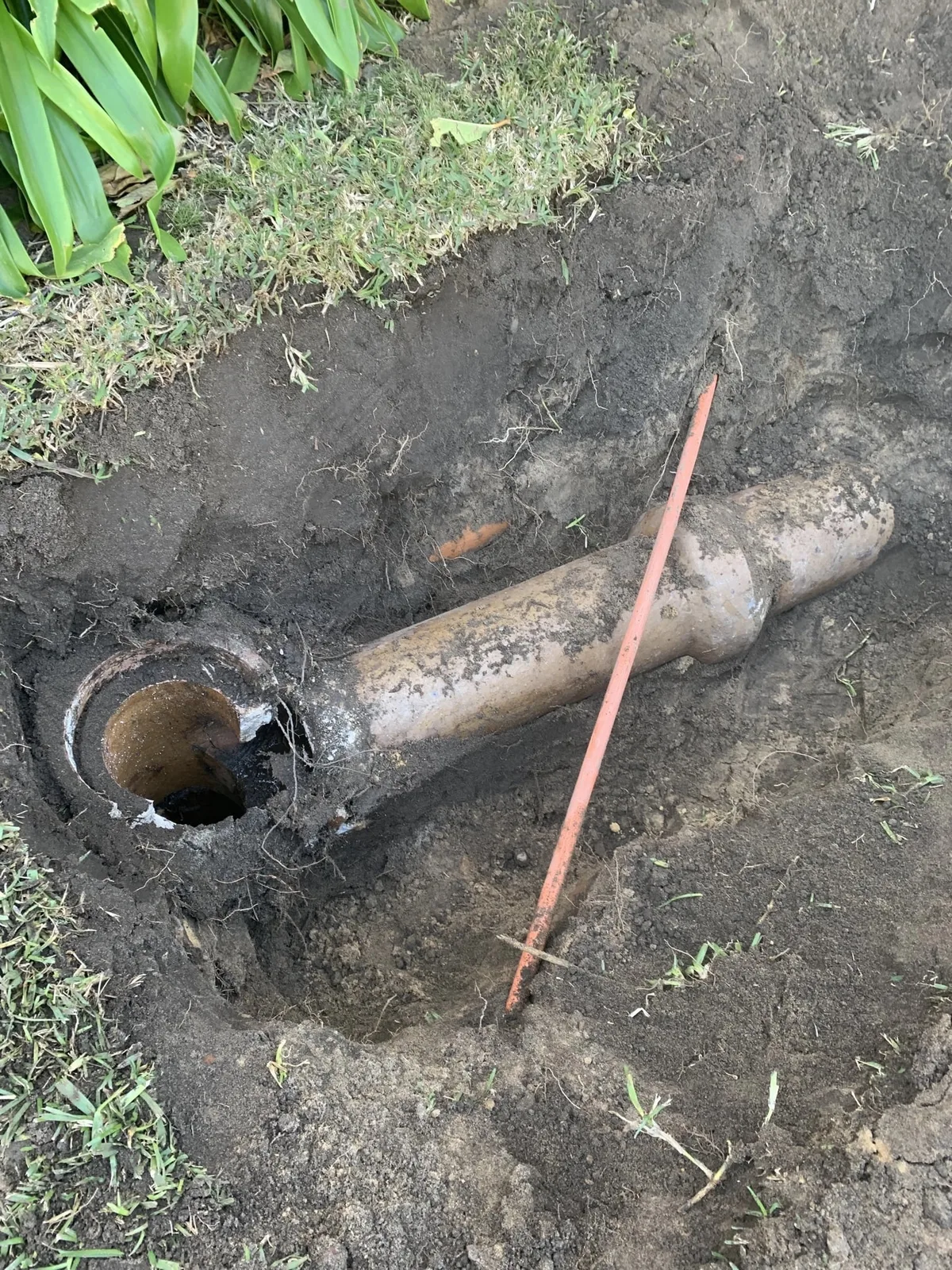 Excavated clay drain pipe exposed for repair